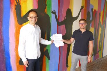 Dr. Drexler und Alexander Biber vor bunt bemalter Wand