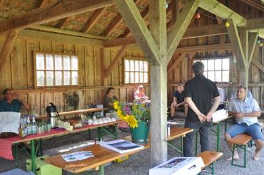 Menschen auf Biertischbänken in Holzgebäude