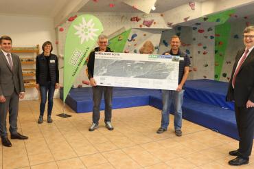 Fünf Personen vor Boulderwand mit Projektinfo Versorgungsleitungen Nördlinger Hütte