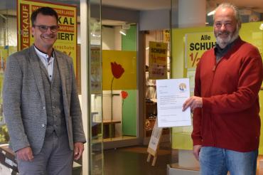 Oliver Sporr (rechts), Geschäftsführer des Stadtladens, übergibt Oberbürgermeister Jürgen Sorré die erste Urkunde als Anteilseigner