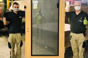 Das Bild zeigt Jonas Herrmann und Heiko Kogel aus der technischen Verglasung, die stolz die 1.000.000 Tür des Jahres 2020 präsentieren.