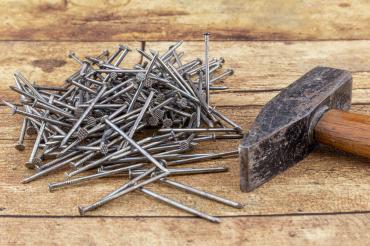 Hammer und ein Haufen Nägel auf einer hölzernen Oberfläche