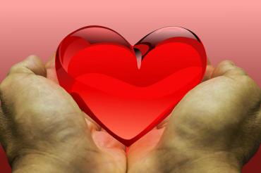 Hände, die ein rotes Herz halten