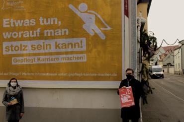 Julia Lux und Stefan Rößle mit Maske vor Plakat der Gesundheitsregionplus Donauries