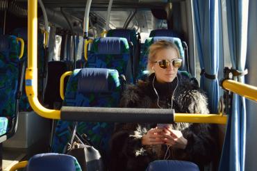 Frau mit Sonnenbrille sitzt im Bus