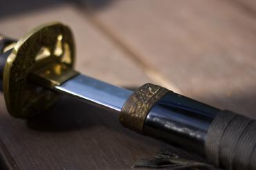 Katana liegt auf Holztisch, ein Stück aus der Scheide gezogen