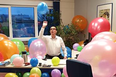 Mann in Büro voller Luftballons