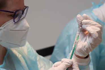 Ärztin mit Mund-Nasen-Schutz zieht Spritze auf