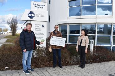 Drei Personen mit Scheck vor SPN Firmensitz