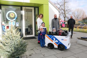 Einrichtungsleiterin Andrea Engelhard, Werner Feil (RVB Ries) und Elternbeiratsvorsitzender Rene Steinmeyer mit Kindern vor dem Montessori-Kinderhaus in Löpsingen. 