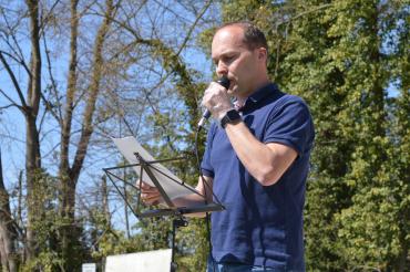 Mann mit Mikrofon vor Bäumen