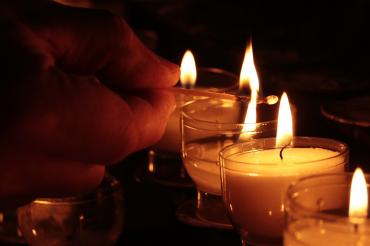 Auf dem Bild sieht man eine Hand, die in Gedenken eine Kerze anzündet.