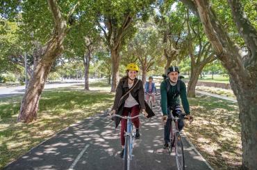 Das Bild zeigt zwei Menschen mit dem Fahrrad auf dem Weg in die Arbeit. 