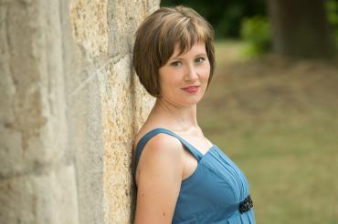 Frau im blauen Kleid lehnt an Mauer