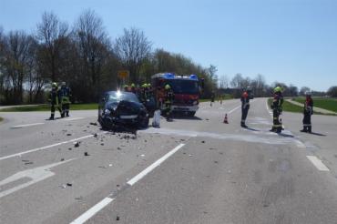 Feuerwehrleute und Feuerwehrauto bei einem Unfallwagen auf einer Straße