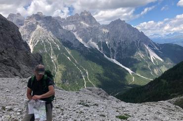 Das Bild zeigt ein Alpenpanorama, im Vordergrund einen Bergsteiger. 