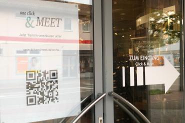 Das Bild zeigt ein Schaufenster des Kaufhaus Woha mit einem Poster als Werbung für Click & meet.