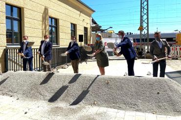 Sechs Personen schaufeln an einem Sandhaufen