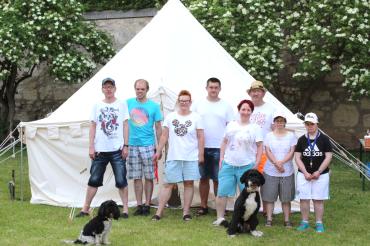 Das Bild zeigt Bewohnerinnen und Bewohner aus der Gruppe 3 vor einem ihrer Zelte