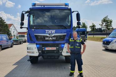 Mann steht vor THW-Fahrzeug