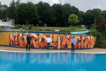 Wolfgang Balzer lässt mit seinem sommerlichen Kunstwerk die Betonwand am Nichtschwimmerbecken im Freibad Nördlingen aufleben. v.l.: Martin Gruber (Leiter Bäderbetriebe), Wolfgang Balzer (Künstler), Oberbürgermeister David Wittner