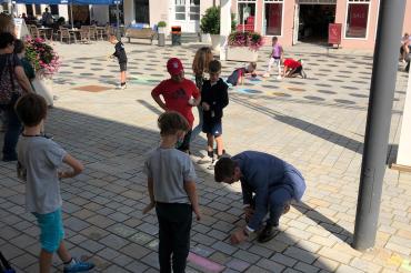 Kinder der Grundschule Mitte mit Außenstel-le Baldingen gestalten die Nördlinger Innenstadt mit Kreide-kunstwerken an den Fußwegen bunt, welche vom Oberbürgermeister David Wittner bewundert wurden.