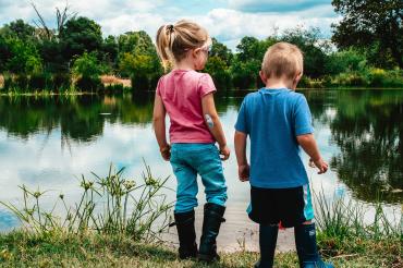 Das Bild zeigt zwei Kinder an einem See. 