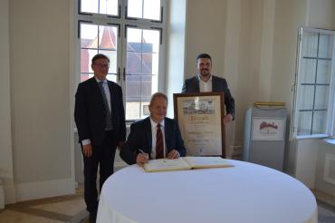 Altbürgermeister Wolfgang Kilian darf sich beim Festakt im Schloss Harburg auch in das goldene Buch der Stadt eintragen. Von links: Landrat Stefan Rößle, Altbürgermeister Wolfgang Kilian und der aktuelle Bürgermeister Christoph Schmidt. 