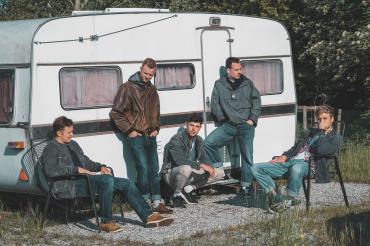 Fünf junge Männer vor Wohnanhänger