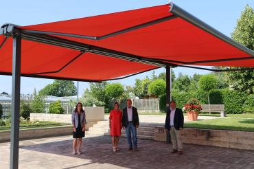 Vier Personen stehen unter einer großen, roten Doppelmarkise