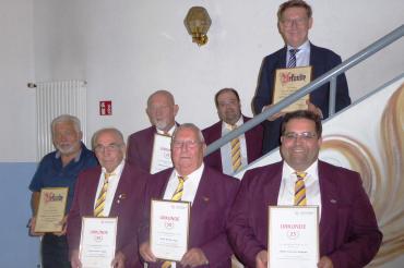 Männer in purpurnen Sakkos bei Treppe mit Urkunden