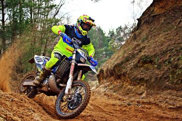 Motocrossfahrer fährt Bike auf sandiger Strecke