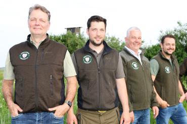 Vier Männer in olivgrünen Westen