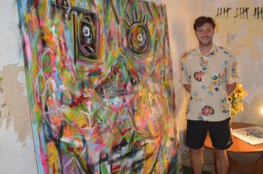 Auf dem Bild zu sehen der Künstler neben einem seiner Bilder. 