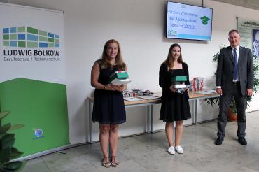 Zwei junge Frauen und ein Mann neben Ludwig-Bölkow-Berufsschule-Roll-Up