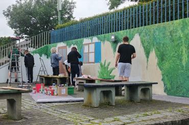 Aus Grau wurde Grün – aus der zuvor grauen Wand entstand unter oftmals grauen Himmel eine gemütlich anmutende Ecke im Pausenhof der Abt-Ulrich-Schule. Eine Ecke die zum Verweilen und staunen einlädt und anregt gemeinsam Großes zu schaffen.