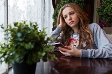 Das Bild zeigt eine junge Frau an einem Tisch sitzend. 