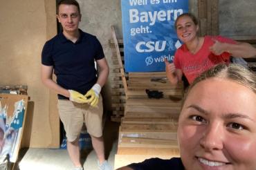 Mann und zwei Frauen vor CSU-Wahlplakat