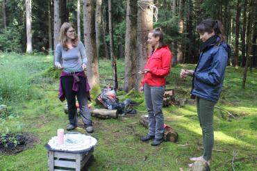 Auf dem Bild zu sehen drei Frauen bei Achtsamkeitsübungen im Wald.