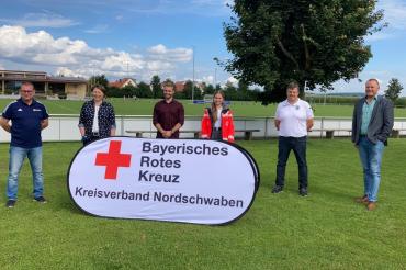 Sechs Personen mit BRK-Aufsteller auf Fußballplatz