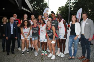 Basketballerinnen in Trikots mit Coach und Sponsoren