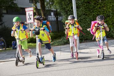 Kinder fahren mit Roller über Straße