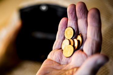 Hand eines alten Menschen hält mehrere Centmünzen