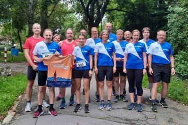 Läufer*innen in blau-weißen Trikots auf Weg bei Bäumen