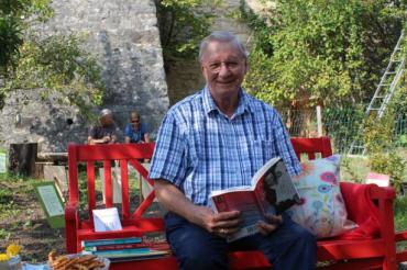 Auf dem Bild sieht man Manfred Hahn mit einem Buch in der Hand. Er wird am 31. Oktober eine Vorlesung im B+ Zentrum Blossenau machen