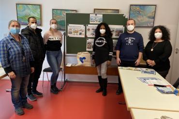 Zwei Männer und vier Frauen stehen vor Tafel in Klassenzimmer