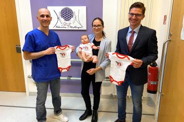 Von links: Chefarzt Kiriakos Savvidis, Christina mit Sara Atalay und Oberbürgermeister David Wittner präsentieren die neuen Bodys mit der Aufschrift "Echtes Rieser Kraterkind". 