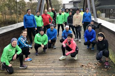 Personen in winterlicher Sportkleidung stehen oder knien auf Brücke in Vorbereitung auf den Jedermannslauf