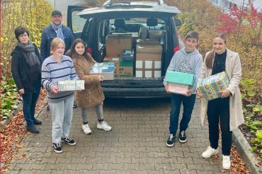 Sechs Personen laden Geschenke in Kofferraum