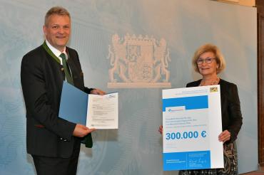 Bayerns Wirtschaftsstaatssekretär Roland Weigert bei der Übergabe des Förderbescheides an die stellvertretende Landrätin Ursula Kneißl-Eder.